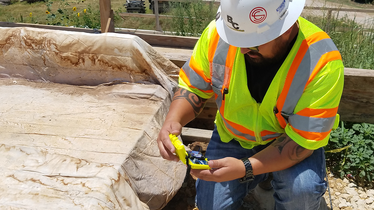 A man uses a COMMAND Center™ Sensor Reader Module to save concrete temperature data.